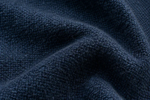 Dense dark blue wool shows individual fibers and a substantial woven fold.