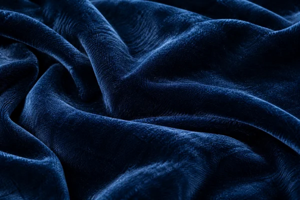Midnight blue velvet in soft folds, showing dense short pile and directional highlights across the fabric.