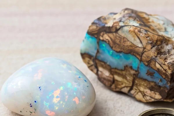White opal with flashes of color beside boulder opal with a blue-green seam.